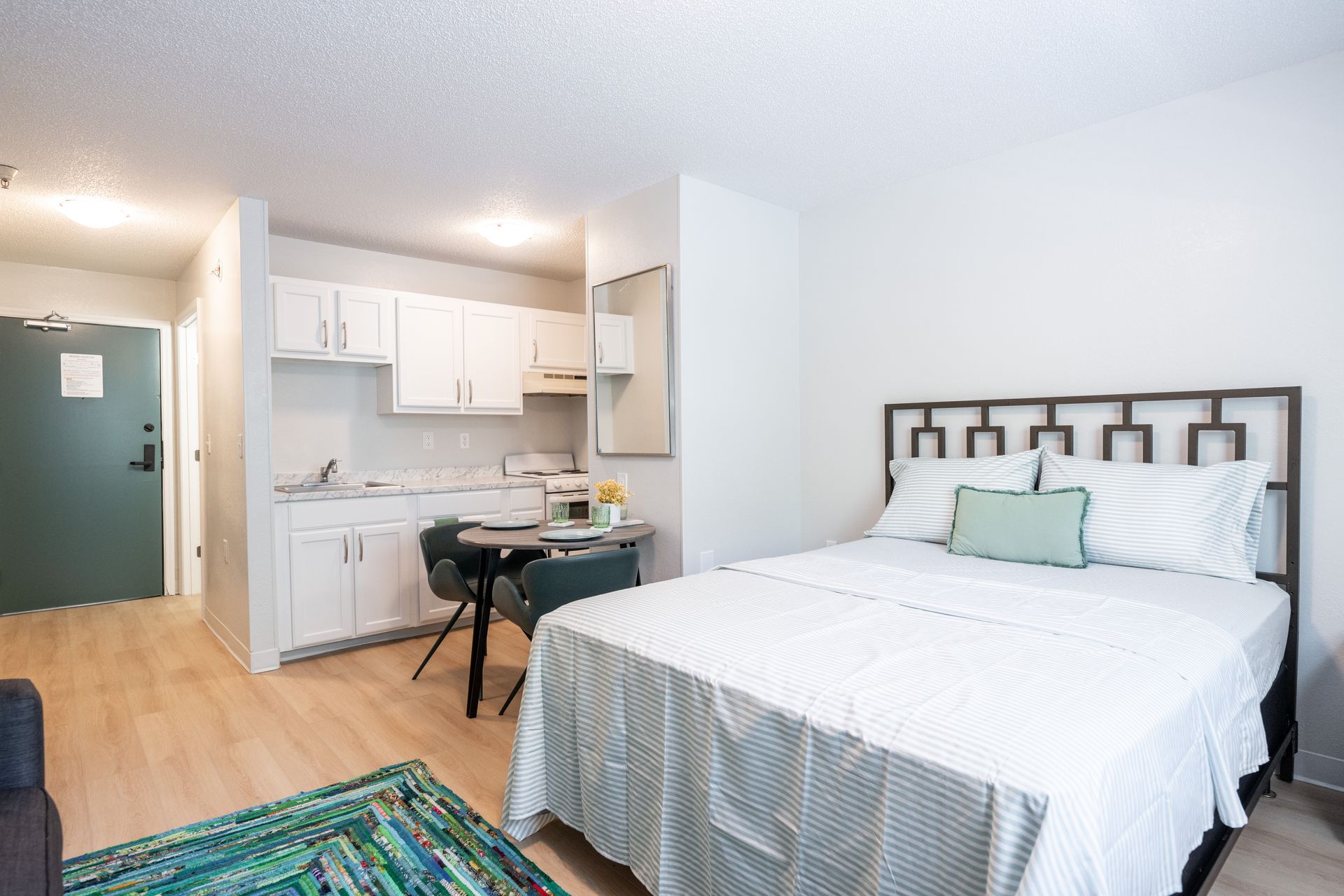 A bedroom with a bed and a kitchen in it.