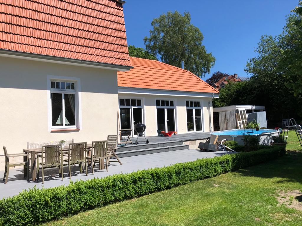 Ein weißes Haus mit einem roten Ziegeldach und einem Swimmingpool