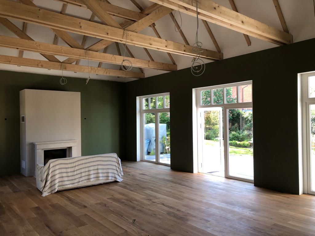 Ein leeres Wohnzimmer mit Kamin und vielen Fenstern.