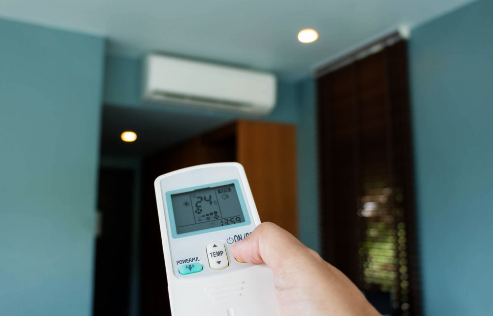 Hand Holding Ac Remote, Adjusting Settings — Brian Williams Electrical Air Solar in Maroochydore, QLD