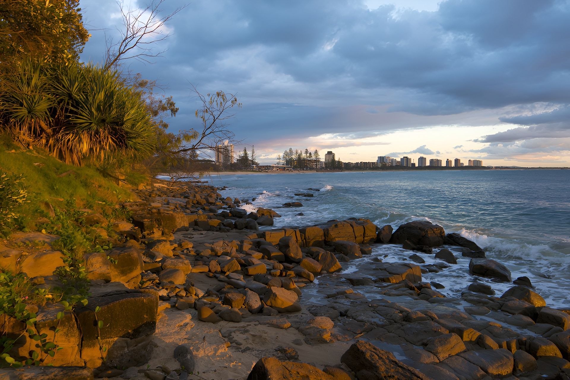 Rocky Shoreline at Sunset With City Skyline — Brian Williams Electrical Air Solar in Maroochydore, QLD