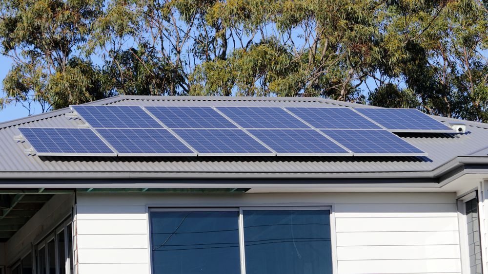 Solar Panels on a Gray Roof, Above a White House With Windows — Brian Williams Electrical Air Solar in Caloundra, QLD