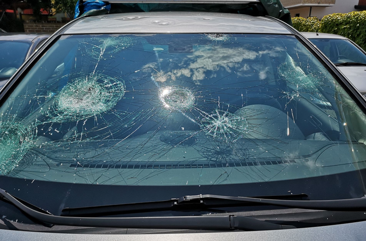 Il parabrezza di un'auto è andato in frantumi a causa di molteplici impatti in un parcheggio.