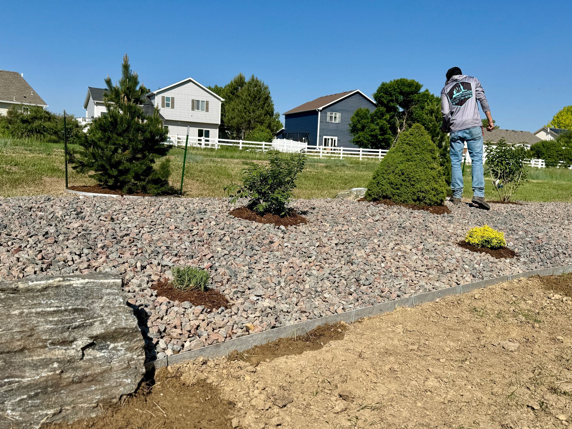 Man planting in rock garden; houses in background.