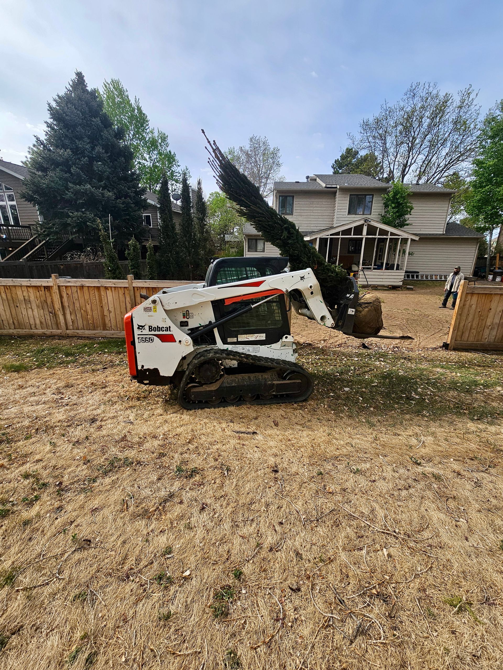 Man working in a rock garden near suburban houses; planting new flowers.