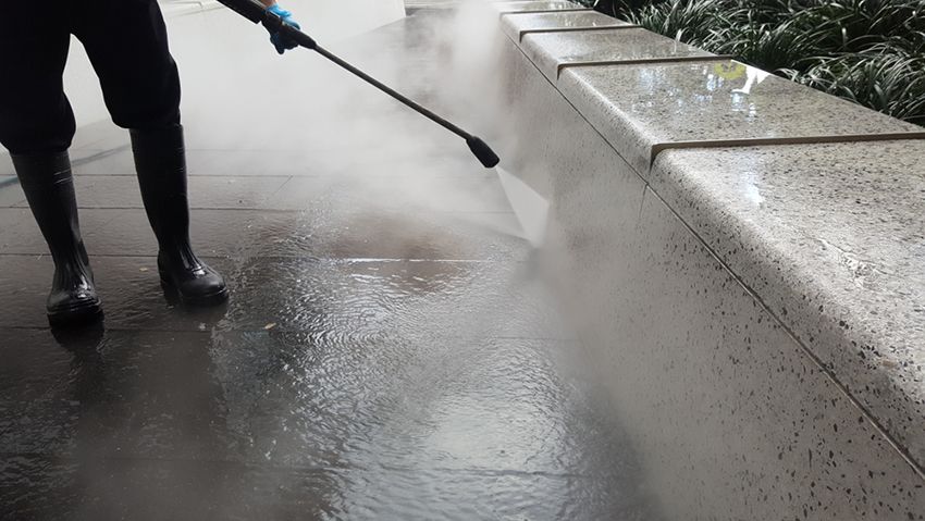 A Person is Using a High Pressure Washer to Clean a Sidewalk — Painters Geelong in Geelong, VIC