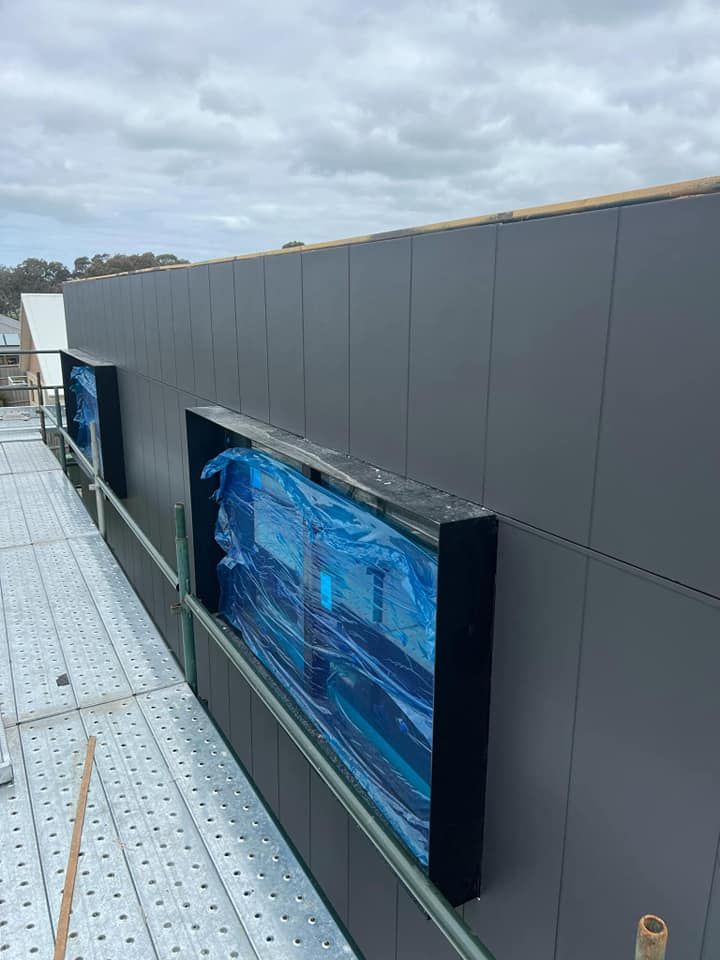 A Man is Painting a Wall in a Room with a Ladder — Painters Geelong in Geelong, VIC