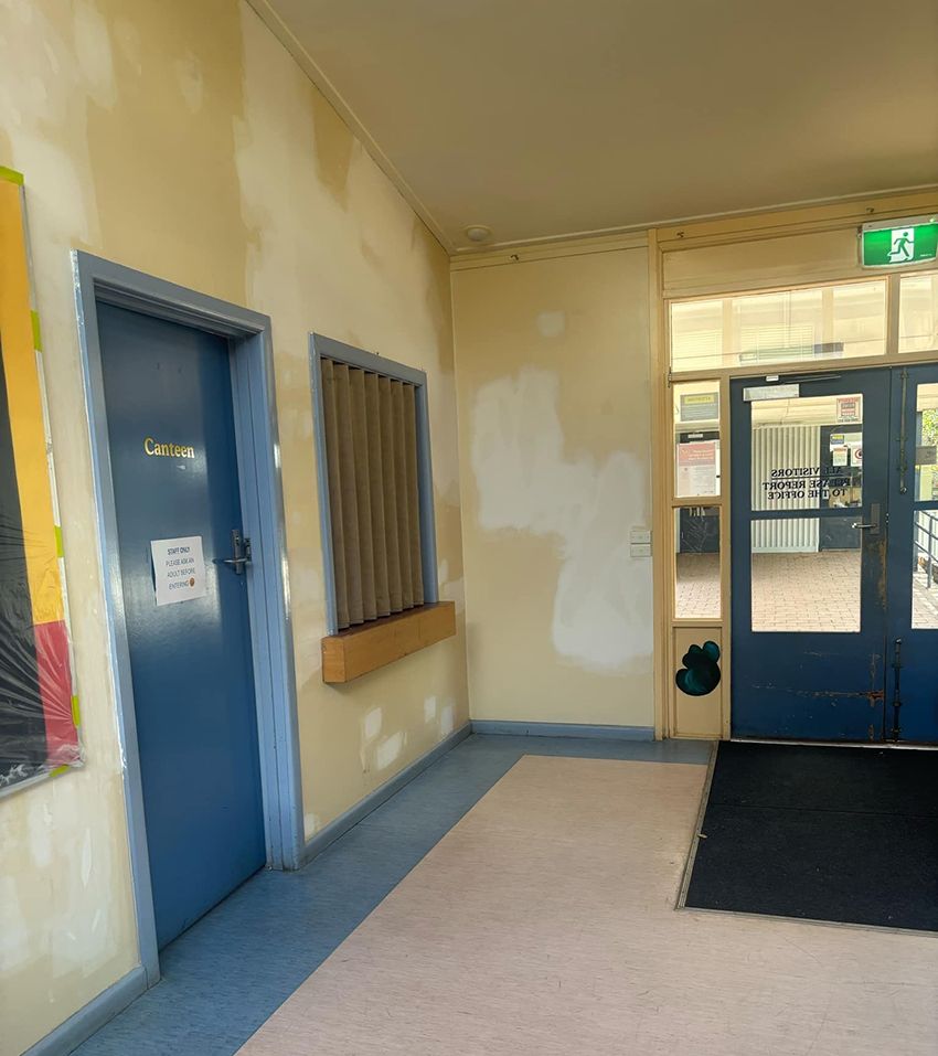 A Hallway with Blue Doors and a Green Exit Sign — Painters Geelong in Geelong, VIC