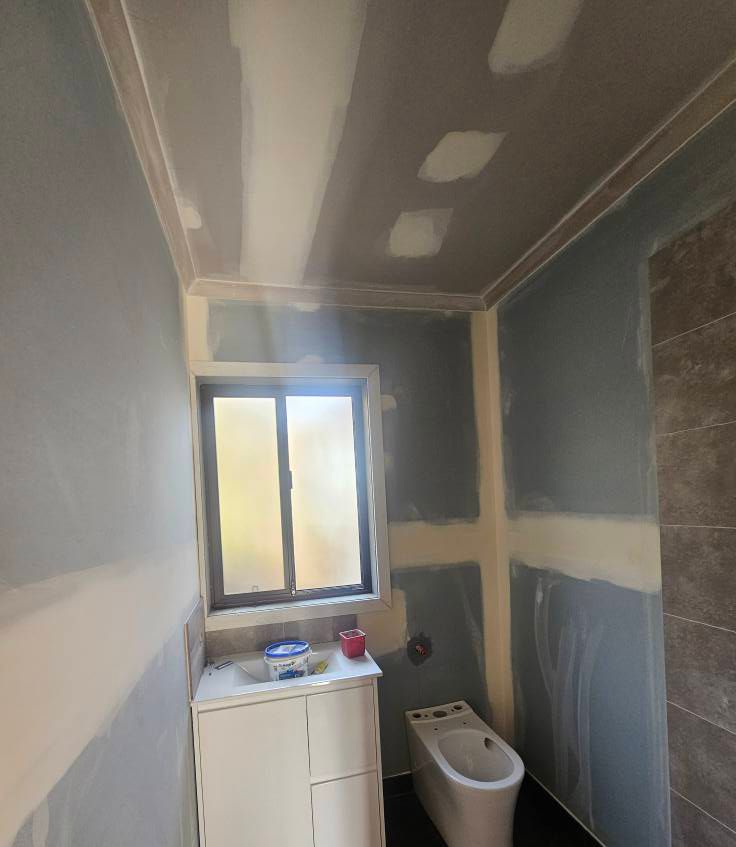 A Bathroom Under Construction with a Toilet, Sink and Window — Painters Geelong in Geelong, VIC
