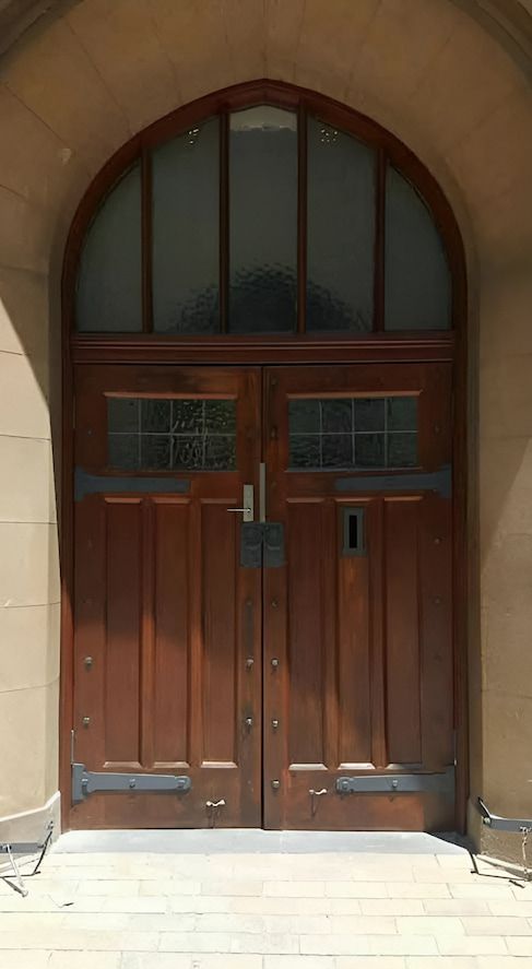 A Wooden Arched Double Door With Glass Panels Set in a Stone Facade — Painters Geelong in Geelong, VIC