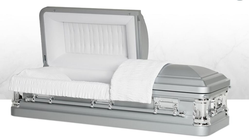 White casket with silver trim and open lid on a plain white background