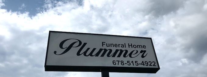 Sign for Plummer Funeral Home against a cloudy sky, with phone number 785-515-4222.