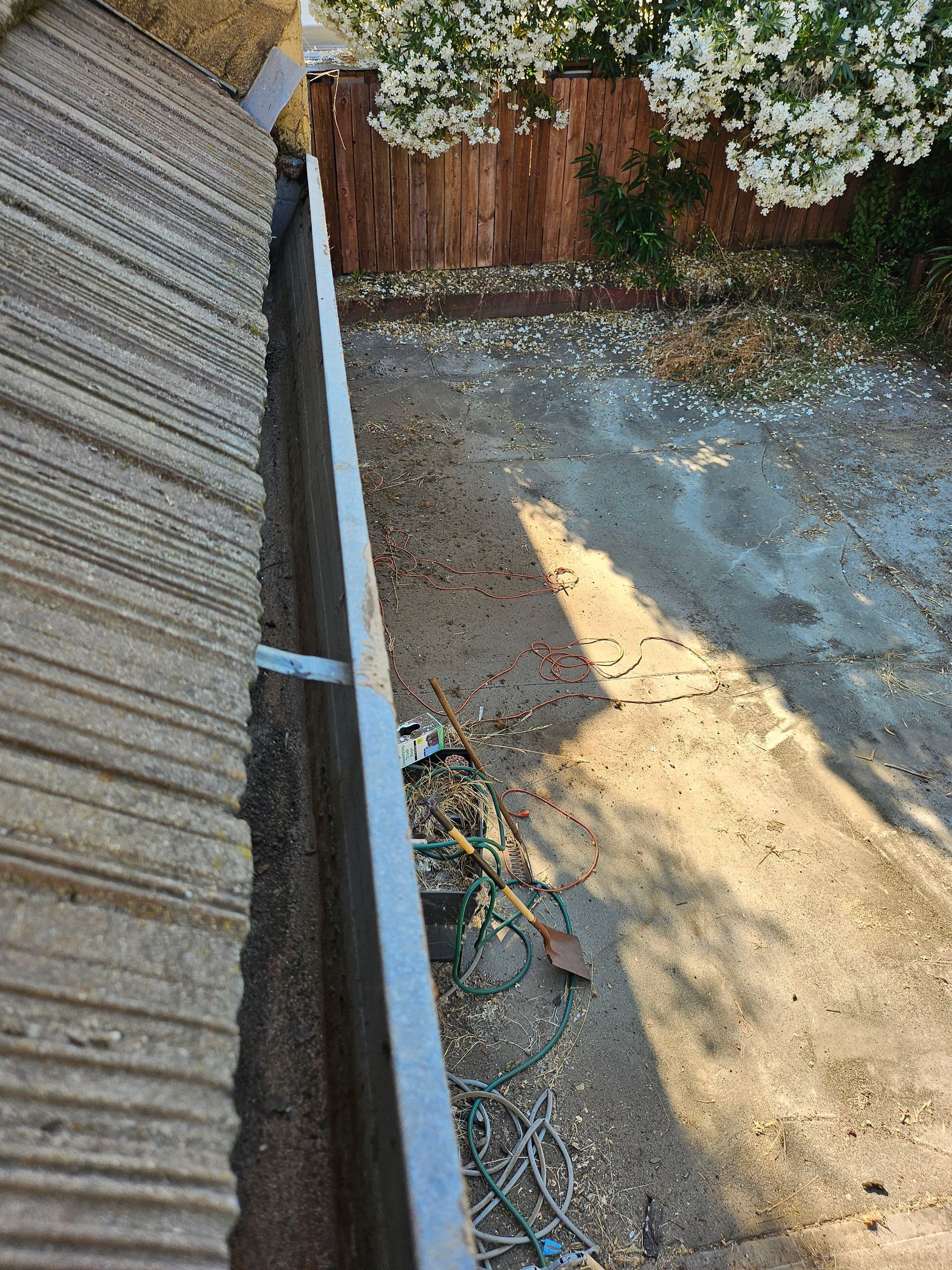 Floodwater pooling beside a brick house wall and downspout after heavy rain