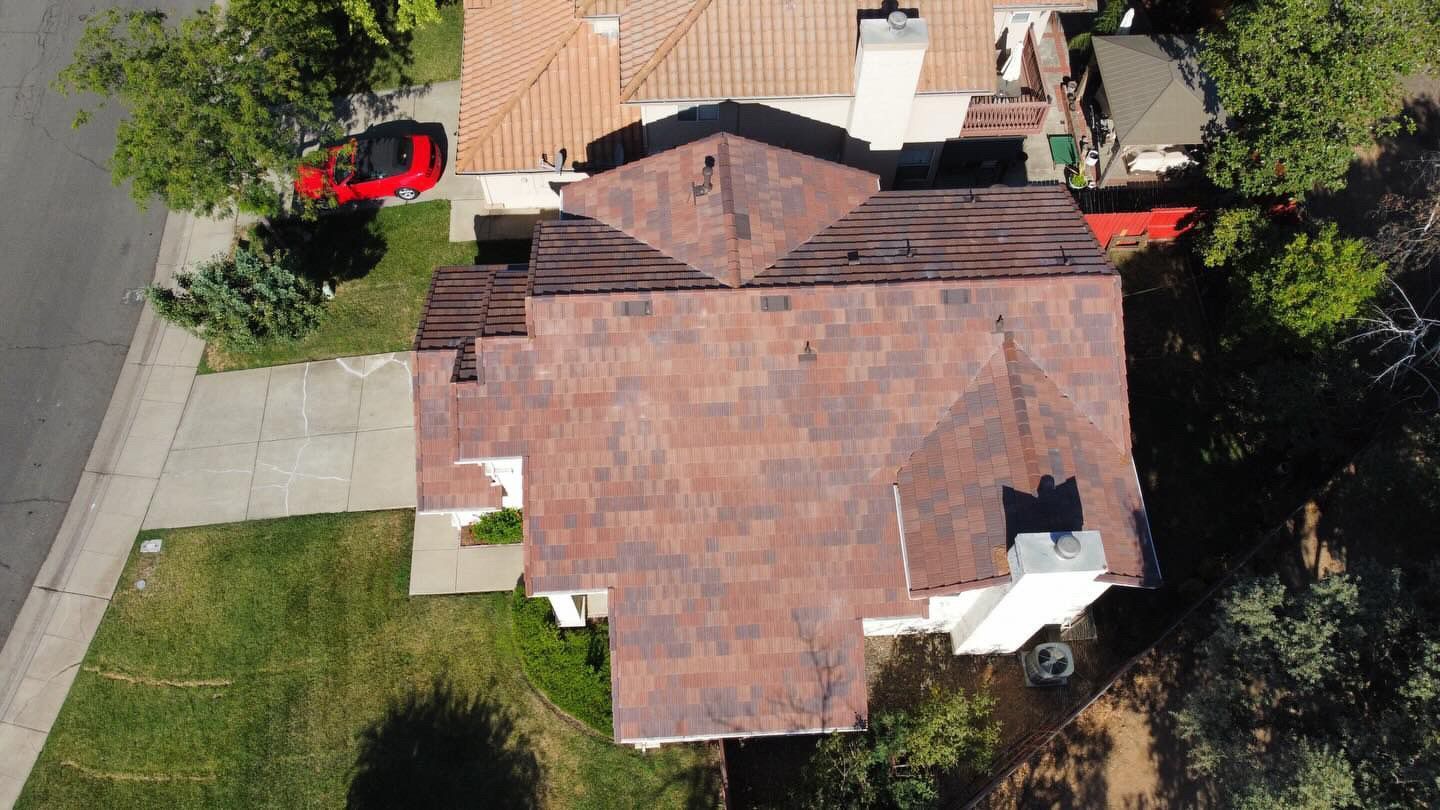 An aerial view of a house with a red car parked in front of it.