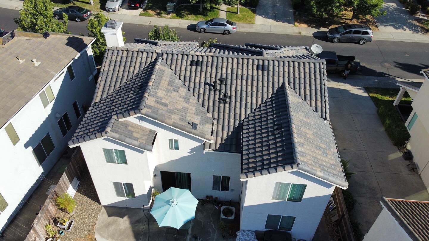 An aerial view of a white house with a black roof.