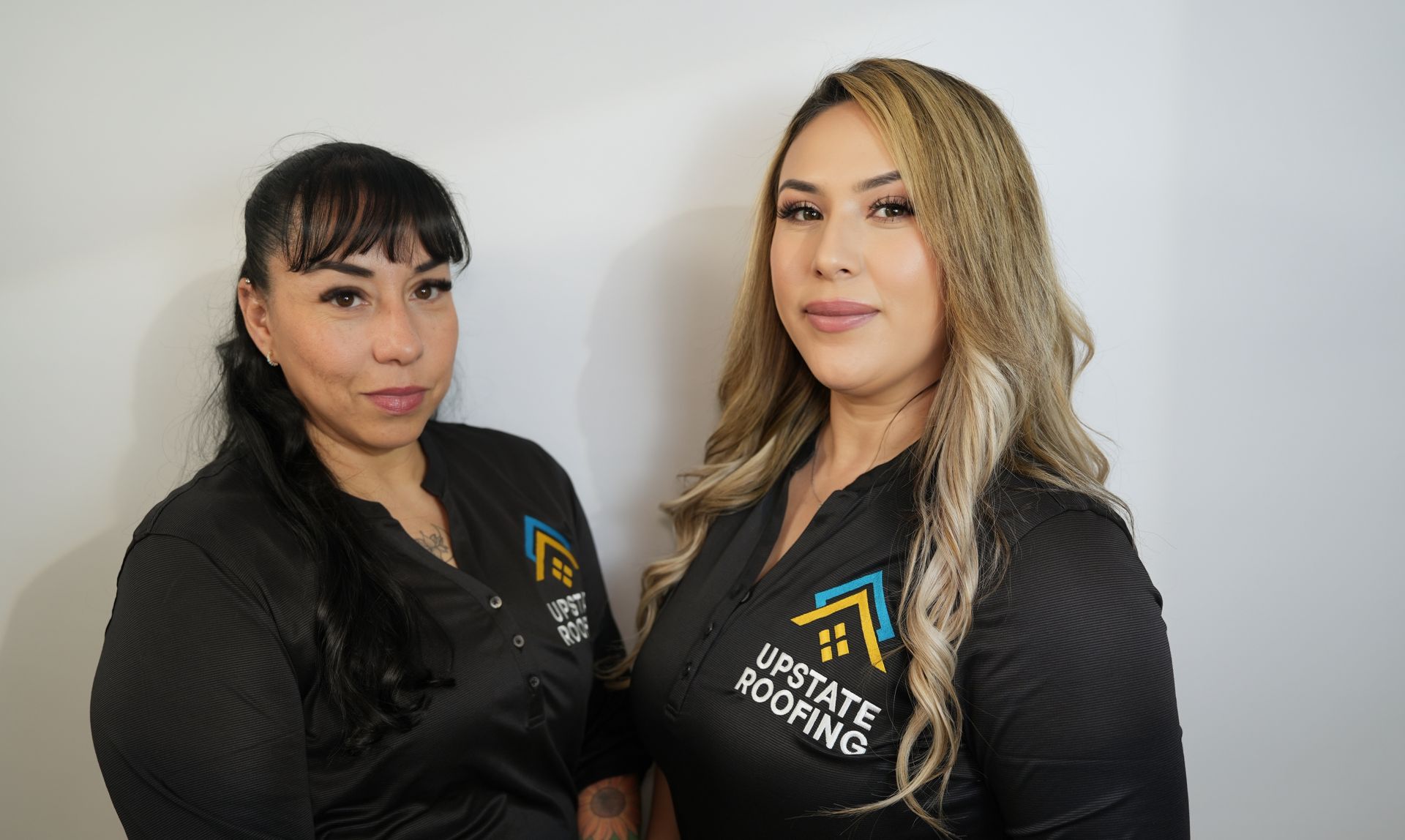 Two women in black jackets posing against a plain white background