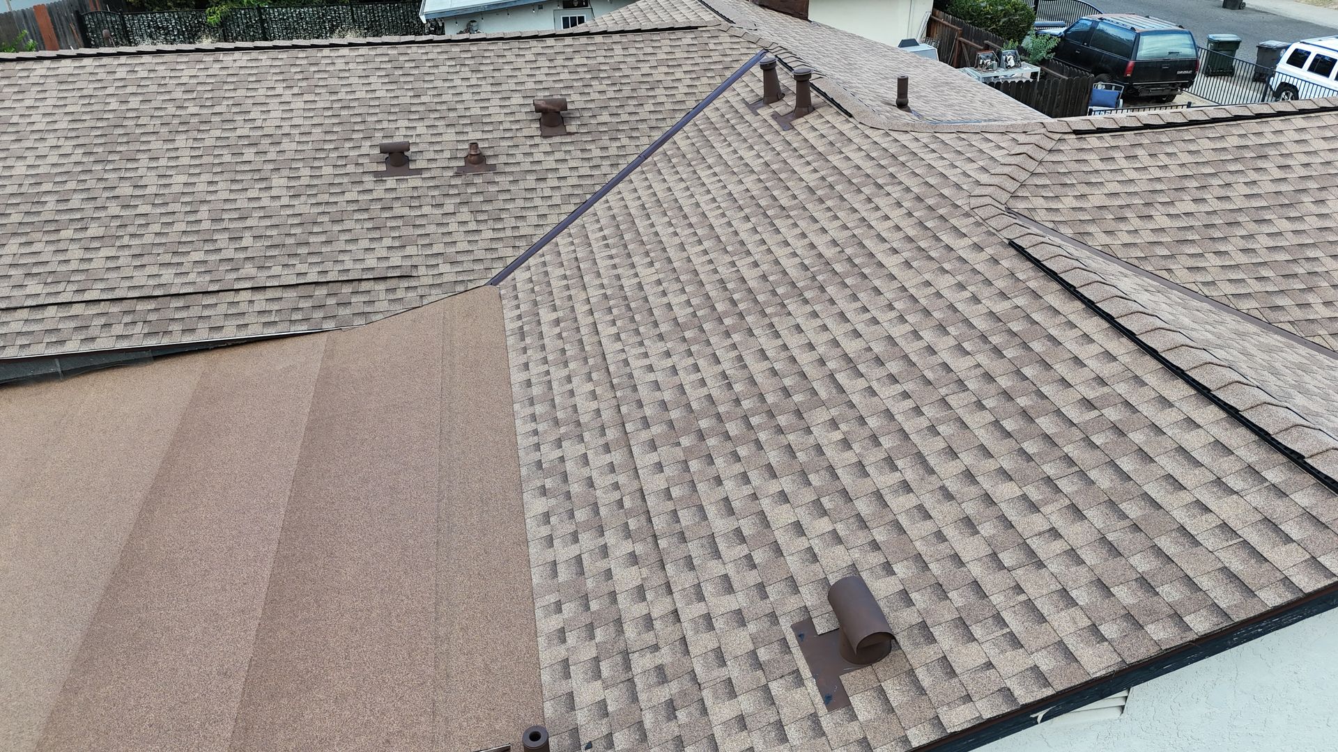 Tan tiled rooftop with vents and parked cars visible beyond the roofline.