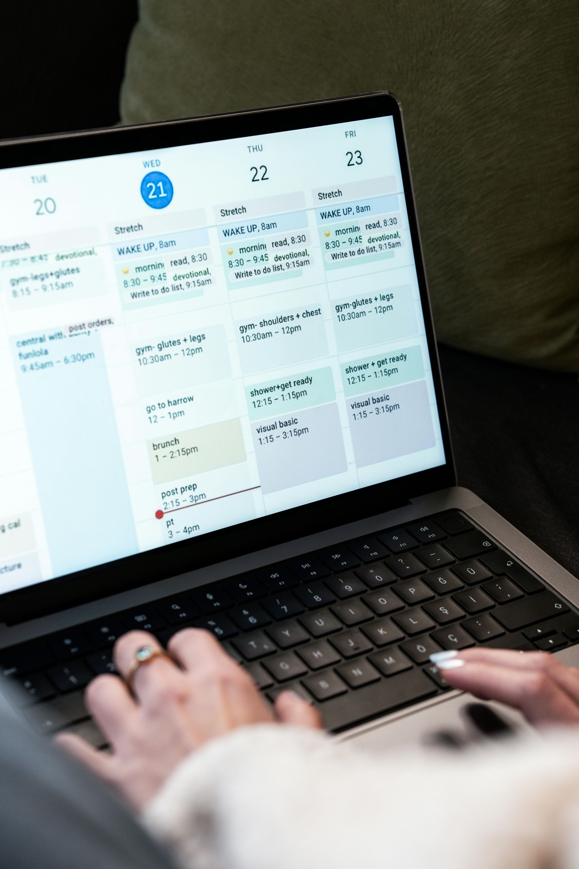 Hands typing on a laptop showing a calendar schedule on screen
