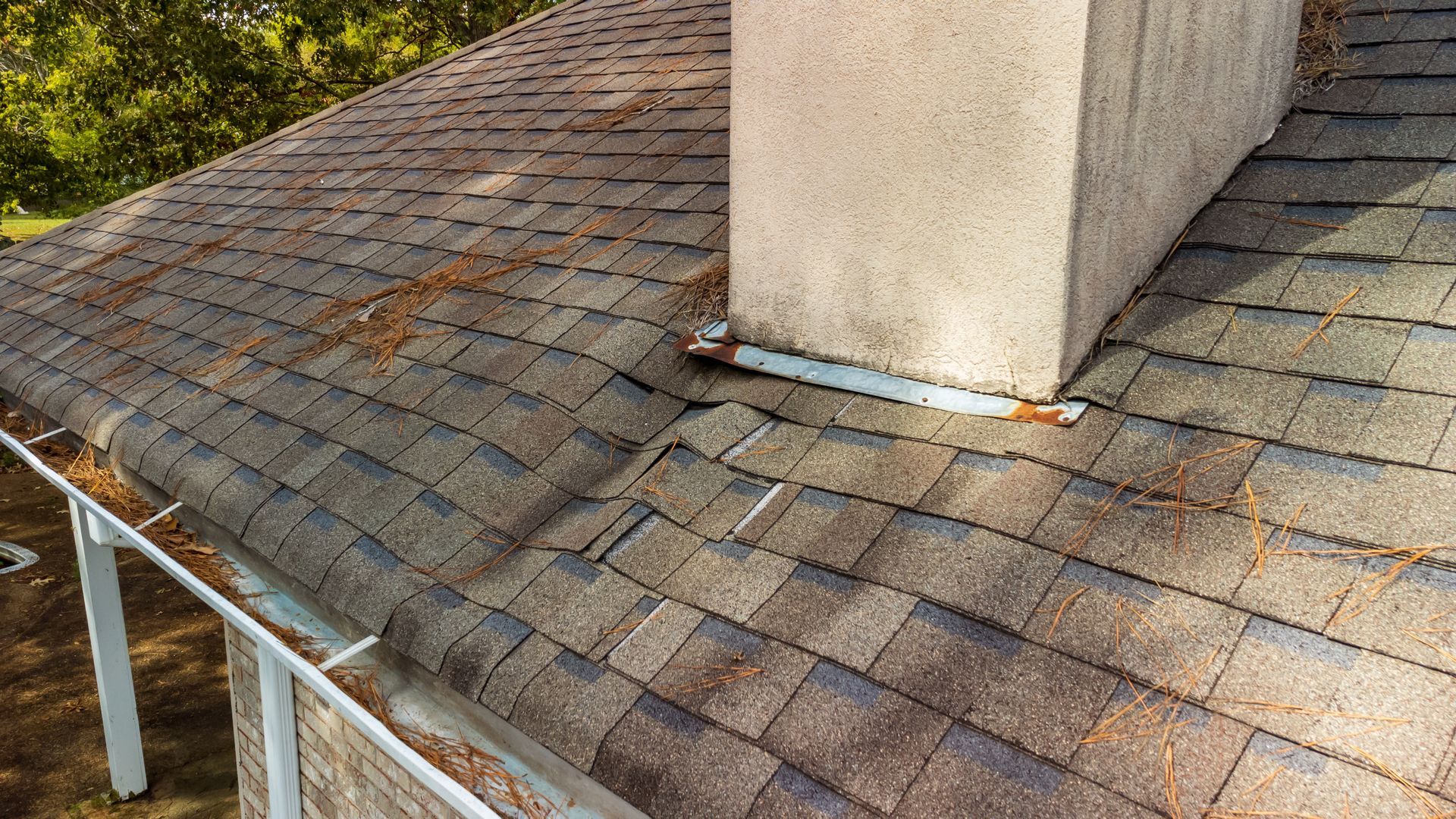 Technician cleaning a roof gutter with a vacuum hose on a beige house