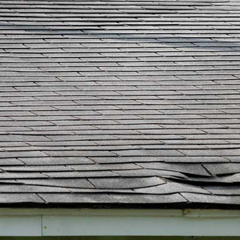 Gray shingled roof with visible damage and curling near the lower edge