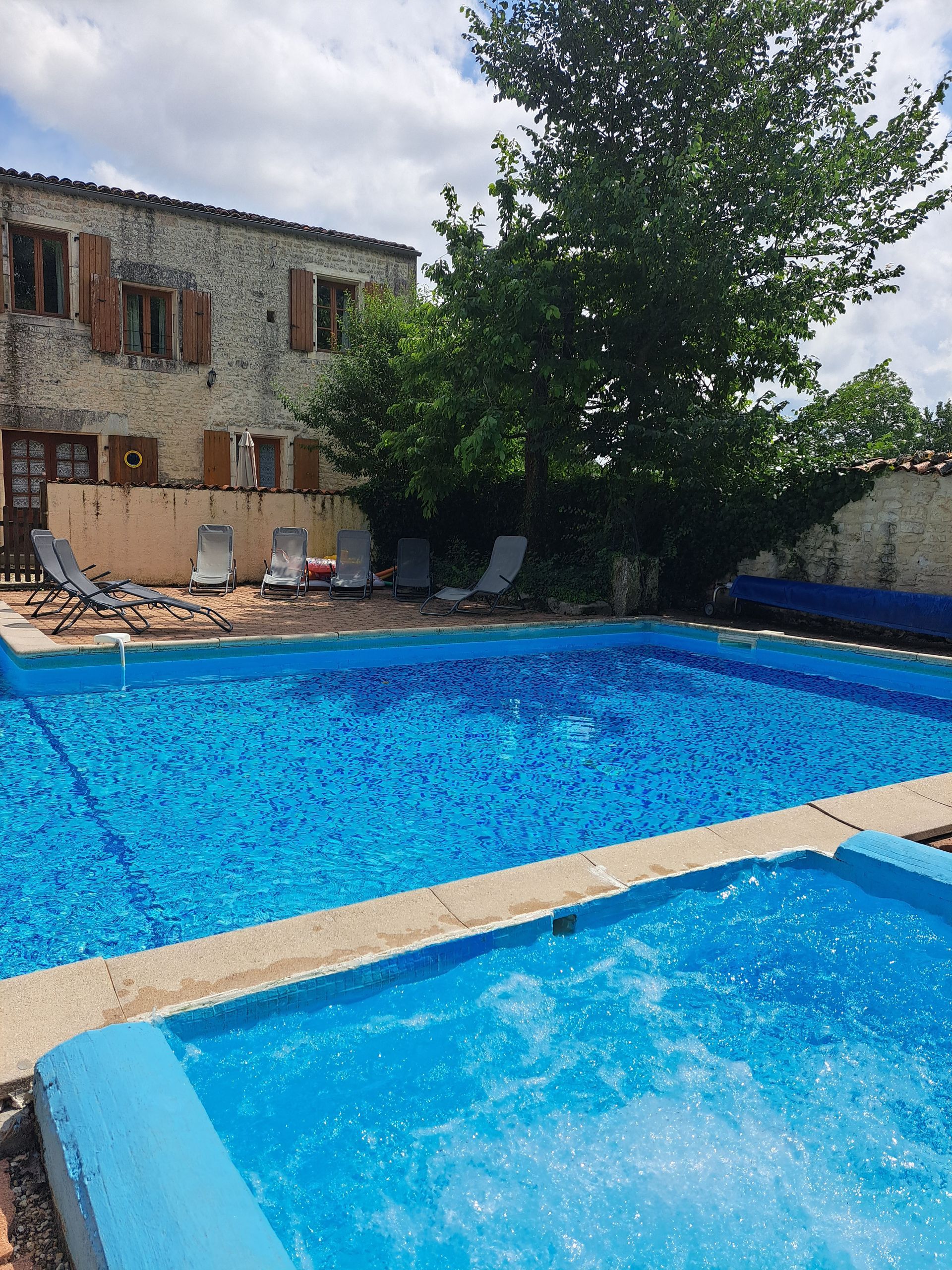 tiled swimming pool and sunbathing terrace with grey sunbeds