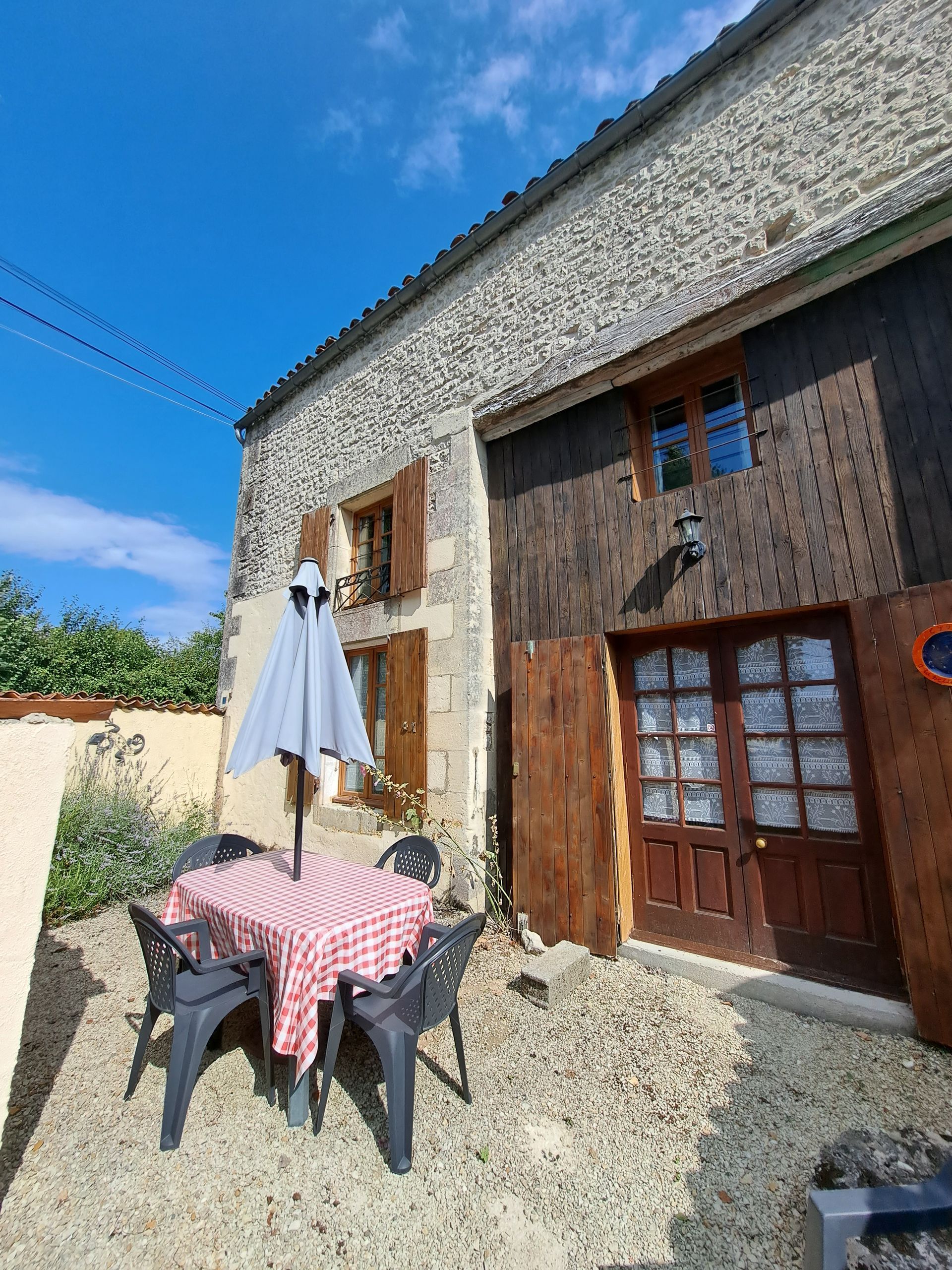 gravelled terrace with garden furniture infront of stone gite with dark wooden front