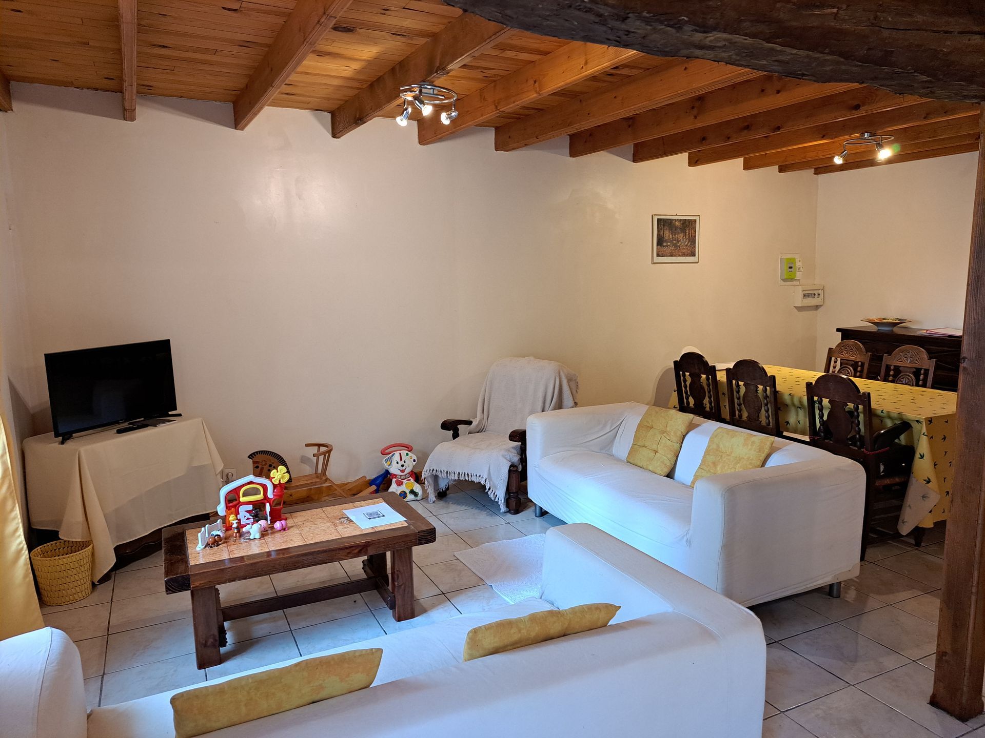 cream ikea sofas with yellow cushions cream walls, wooden ceiling beams