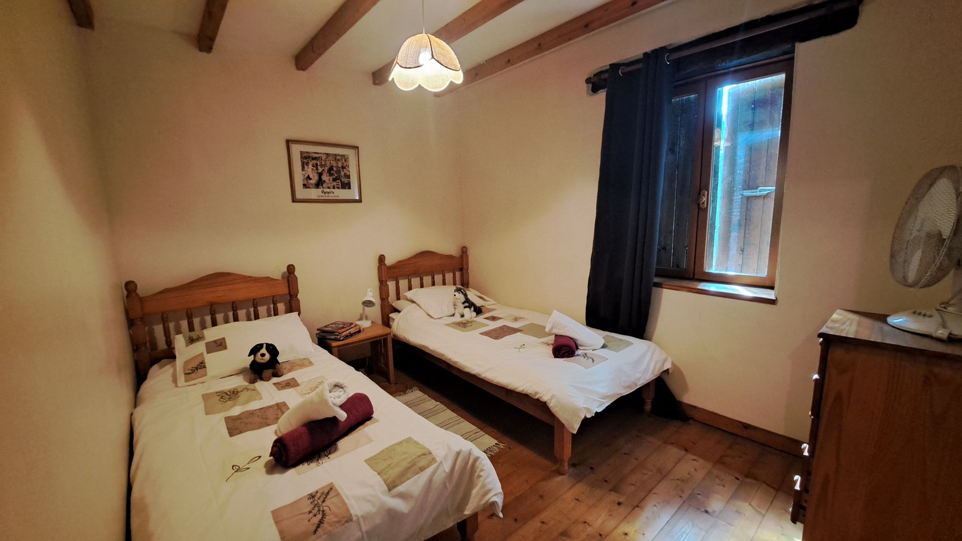 Twin beds in room with wooden floorboards and beams