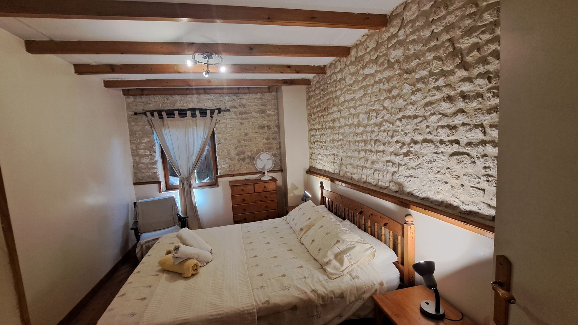 king sized pine bed with exposed stone walls behind