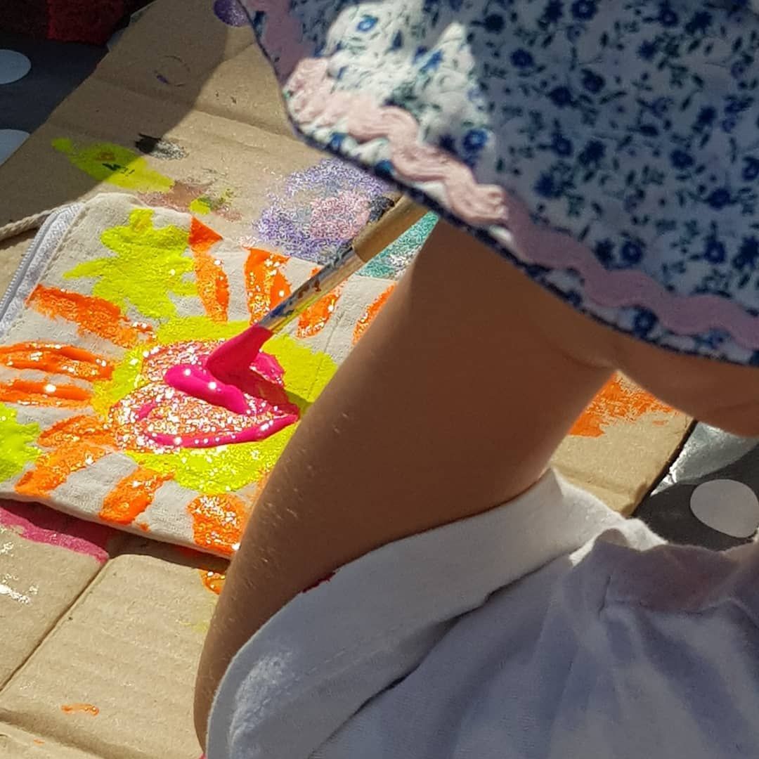 child fabric painting a sunshine onto a cotton purse