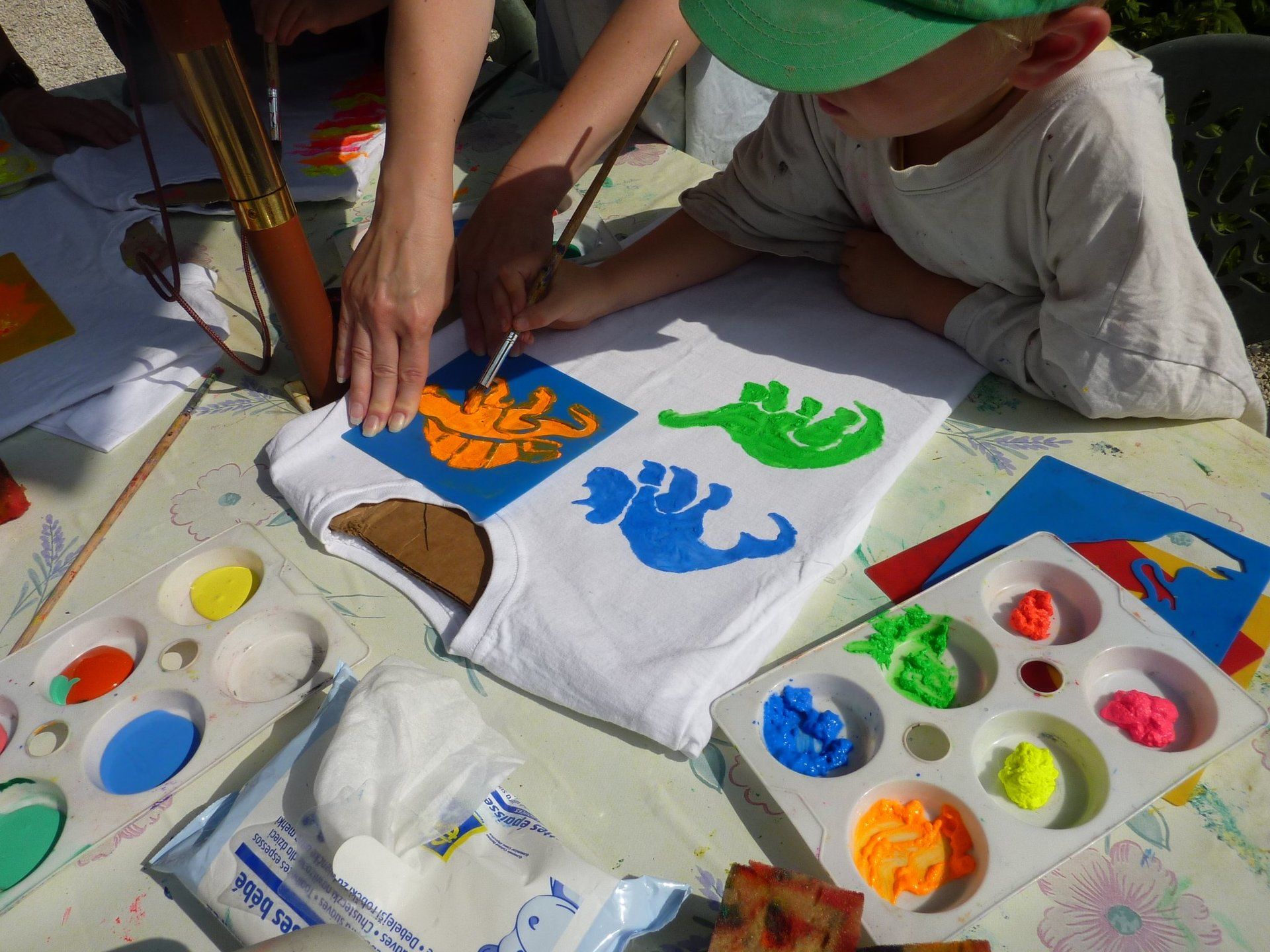 a child using dinisaur stencils to fabric paint on a white t-shirt