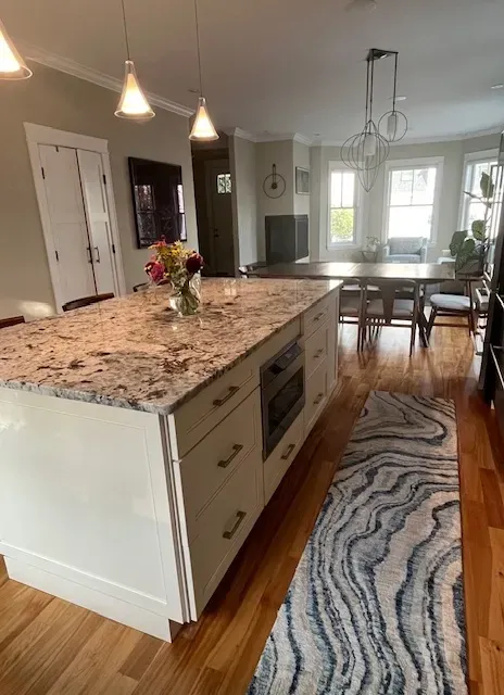 A kitchen with a large island and a rug on the floor.