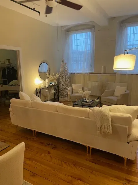 A living room with white furniture and a ceiling fan