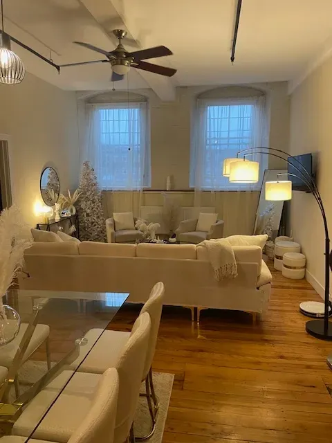 A living room with white furniture and a ceiling fan