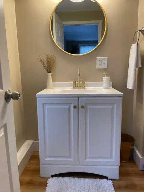 A bathroom with a sink and a round mirror