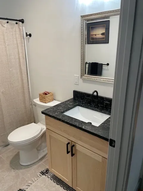 A bathroom with a toilet , sink and mirror