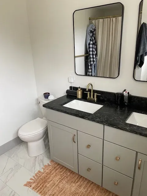 A bathroom with a toilet , sink , and mirror.
