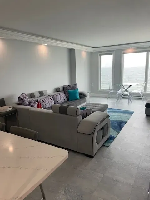 A living room with a couch and a table with a view of the ocean