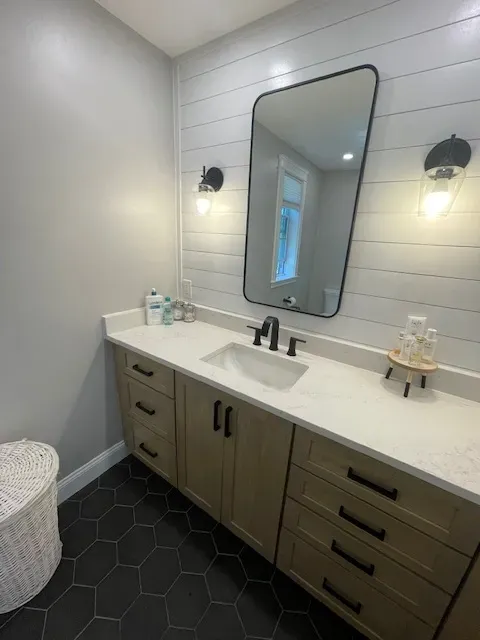 A bathroom with a sink , mirror and cabinets.