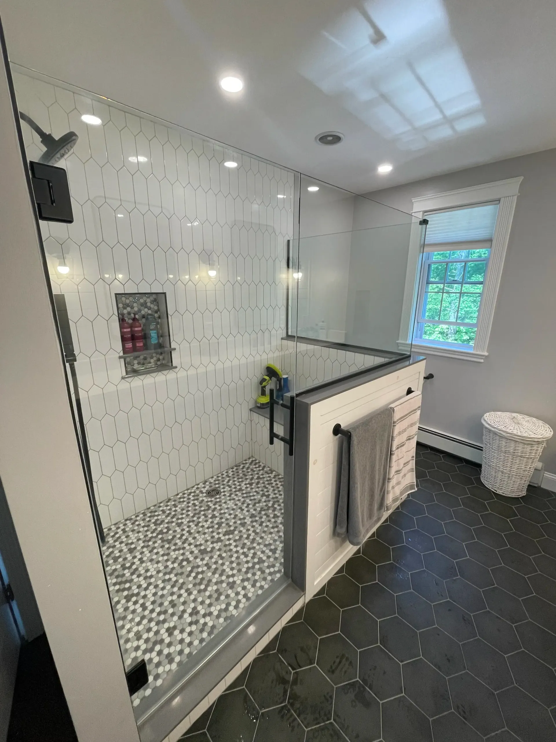 A bathroom with a walk in shower and a window.