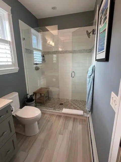 A bathroom with a toilet , sink and walk in shower.