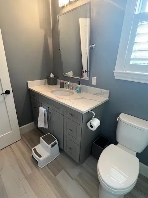 A bathroom with a toilet , sink and mirror