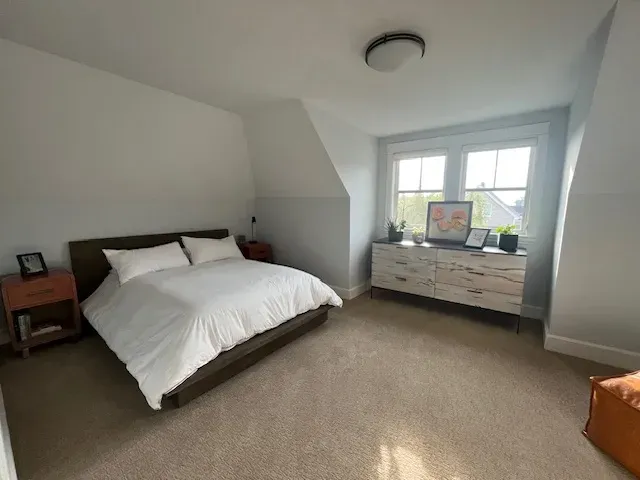 A bedroom with a bed , dresser , nightstand , and window.