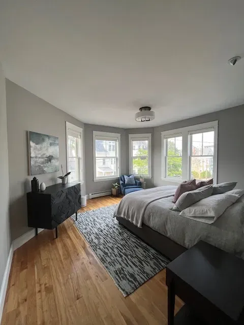 A bedroom with a large bed , dresser , chair and rug.