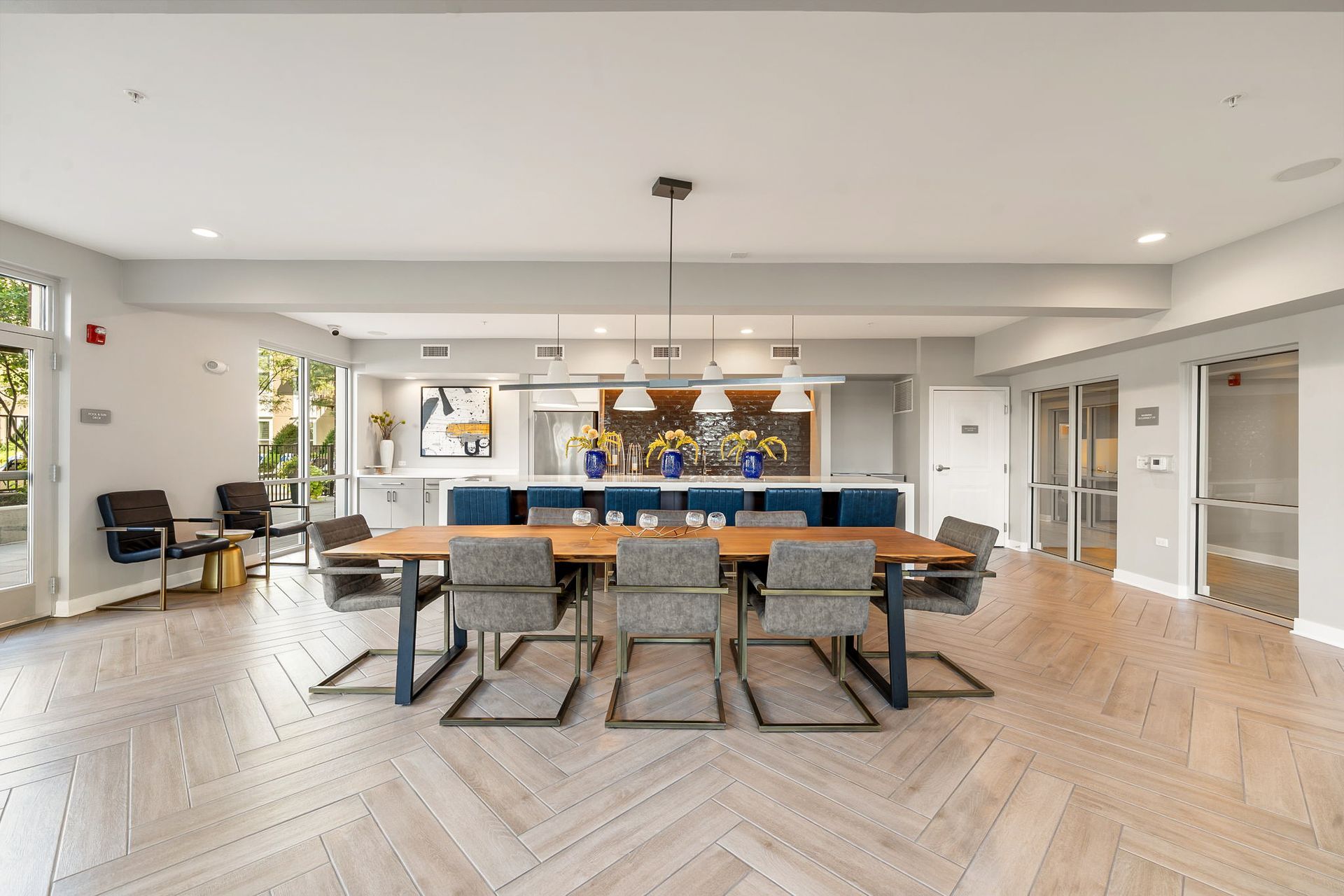 Spacious, bright dining area with a long wooden table and modern chairs, next to a kitchen island.
