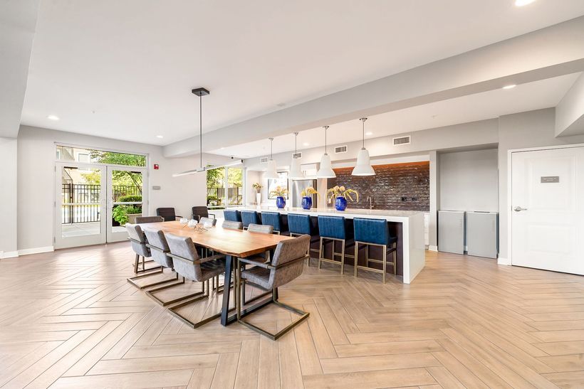 Spacious dining room with a long table, a kitchen island, and seating, with wooden floors.