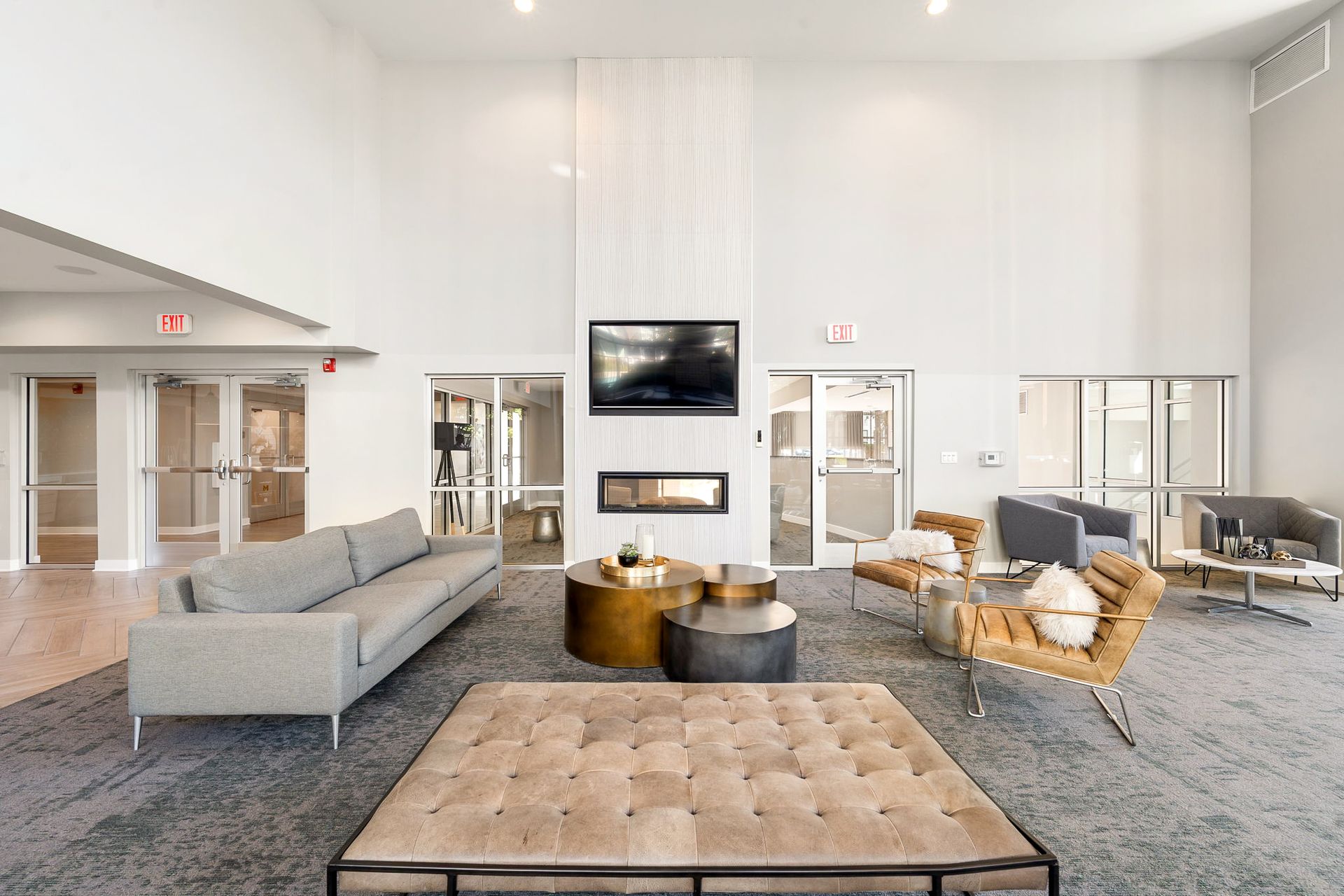Spacious lobby with seating, fireplace, and large-screen TV. Neutral tones with natural light and multiple exits.