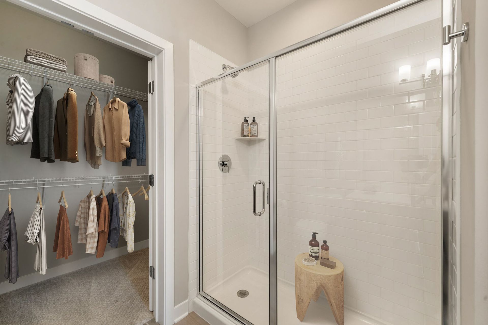 Bathroom with a glass shower, walk-in closet visible on the left, small wooden stool, neutral colors.