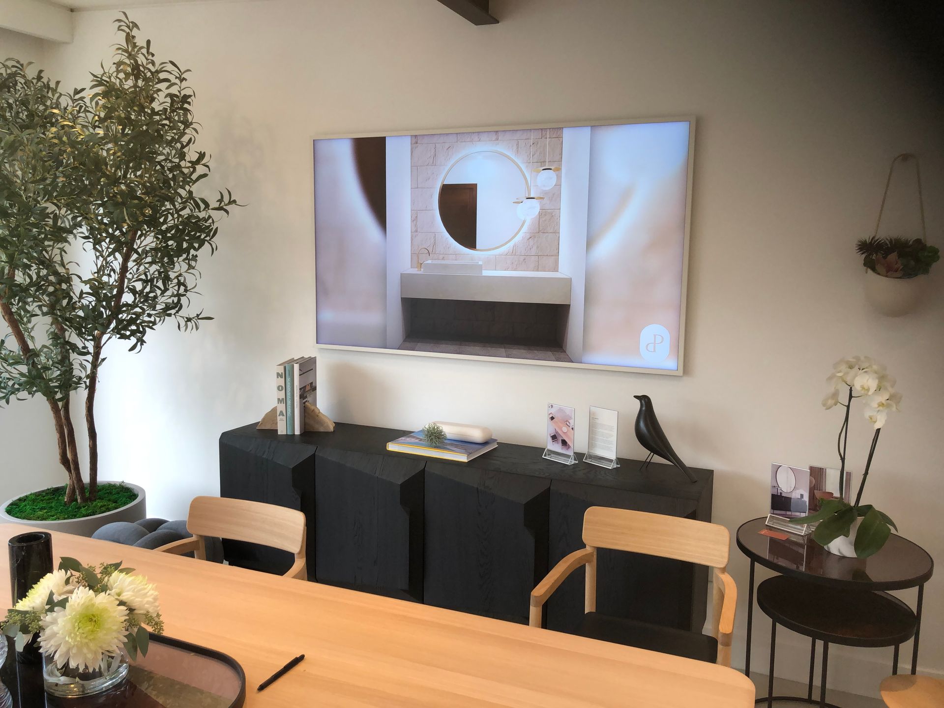 A large flat screen tv is hanging on the wall above a table.