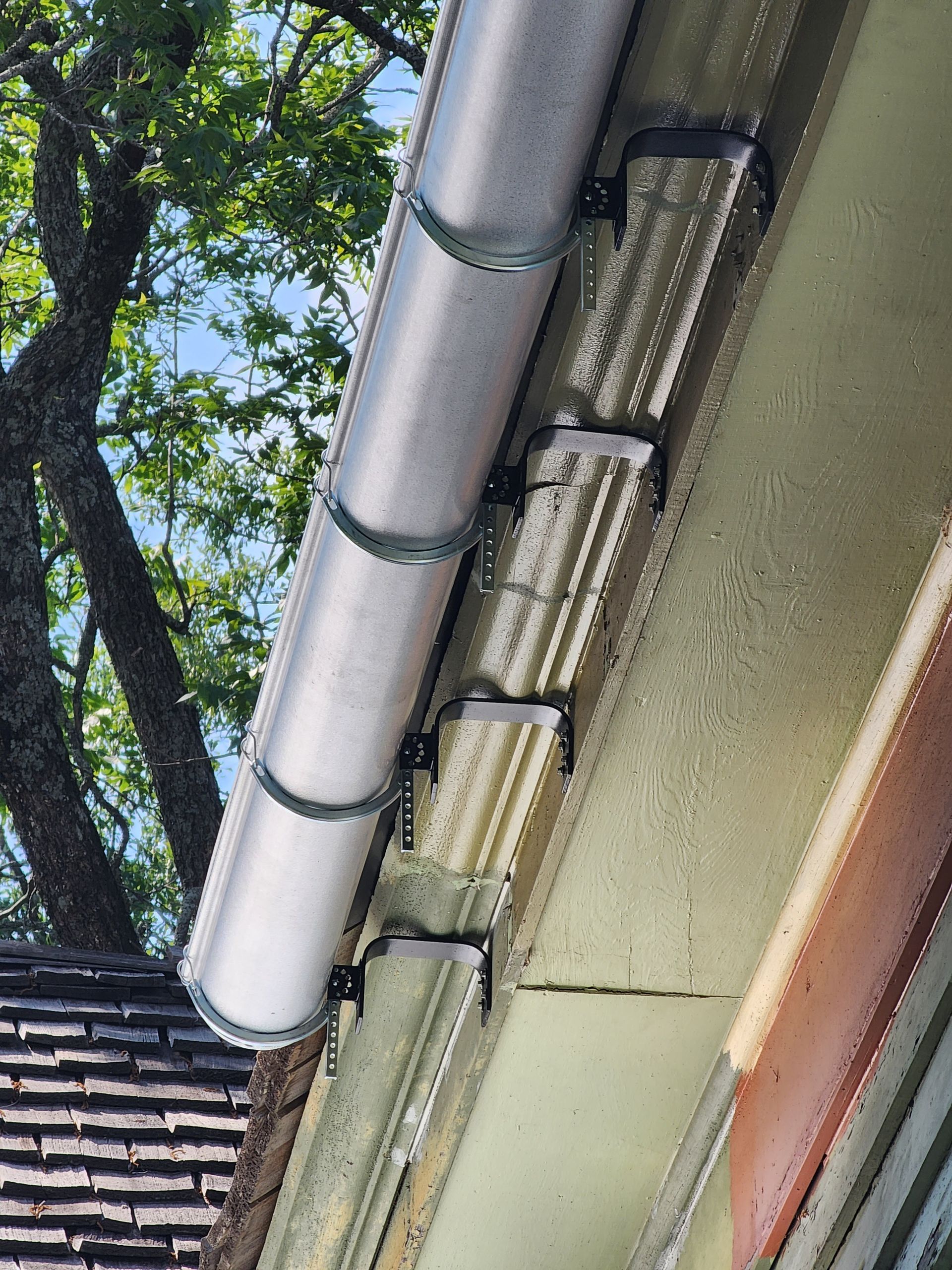 Aluminum gutter attached to a building's trim, with mounting brackets.